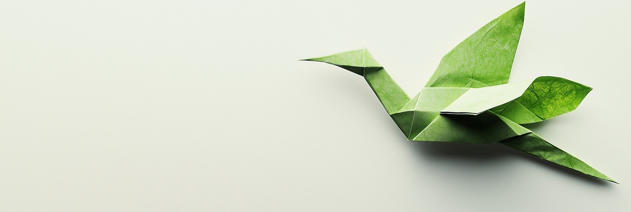 Origami-Kranich aus grünem Papier mit Blattadern auf hellem Hintergrund.