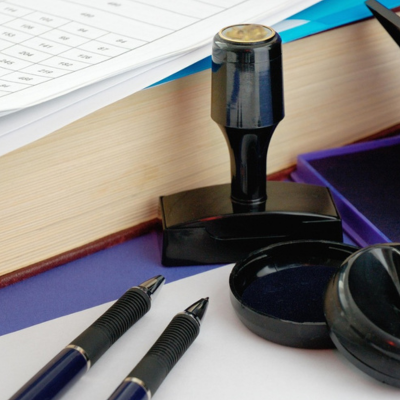 Stempel und Stempelkissen neben Federn und Papier auf dem Schreibtisch.