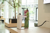 Rednerin steht hinter weißem Pult, Rechner steht aufgeklappt auf dem Pult