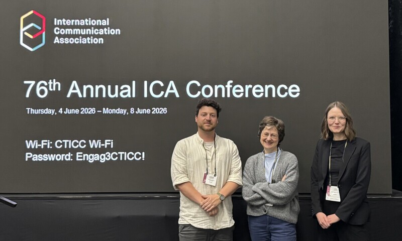 Drei Personen vor einer Wand der 76. ICA-Jahreskonferenz der International Communication Association.
